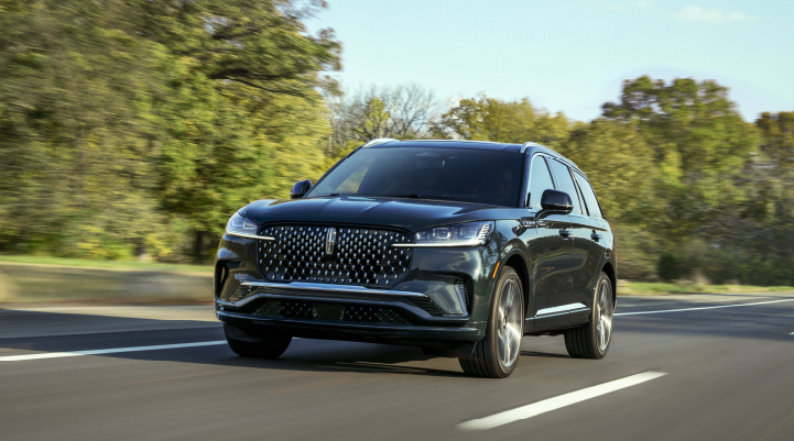 A 2025 Lincoln Black Label Aviator® SUV is being driven down a road lined with trees. | McLarty Daniel Lincoln in Bentonville AR