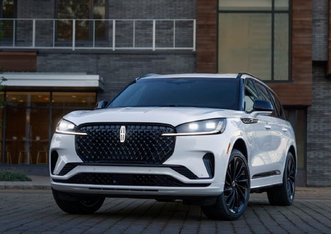 A 2026 Lincoln Aviator® Reserve model is shown with the available Jet Appearance Package parked near a restaurant. | McLarty Daniel Lincoln in Bentonville AR