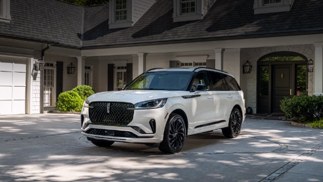 A white 2026 Lincoln Aviator® SUV is parked in the driveway of a luxury home. | McLarty Daniel Lincoln in Bentonville AR