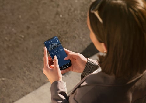 A person is shown interacting with a smartphone to connect to a Lincoln vehicle via the Lincoln Way® app. | McLarty Daniel Lincoln in Bentonville AR