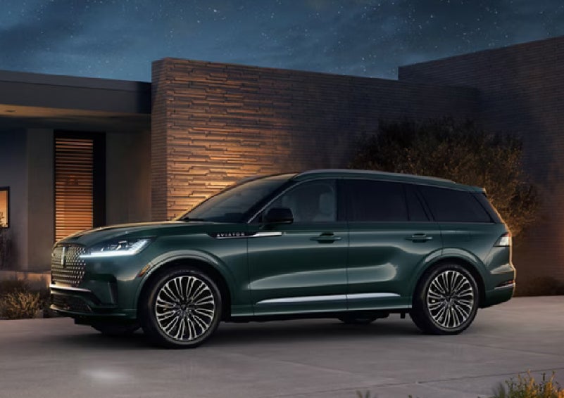 A green 2027 Lincoln Aviator® SUV is parked outside a contemporary home. | McLarty Daniel Lincoln in Bentonville AR