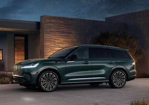 A green 2027 Lincoln Aviator® SUV is parked outside a contemporary home. | McLarty Daniel Lincoln in Bentonville AR