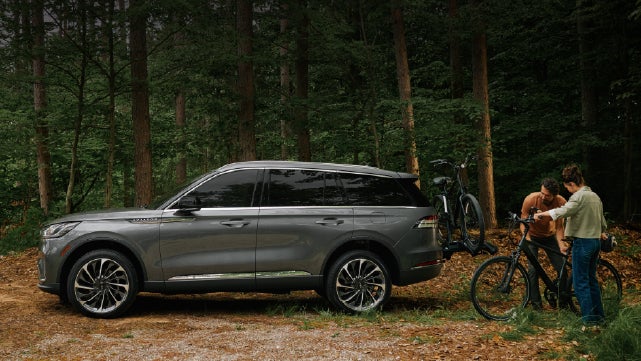 A father and son load e-bikes on a bike rack attached to a 2027 Lincoln Aviator® SUV. | McLarty Daniel Lincoln in Bentonville AR