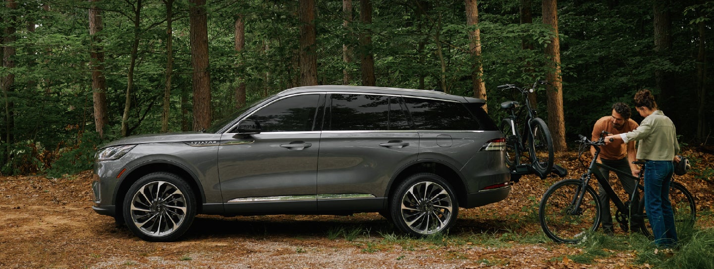 A father and son load e-bikes on a bike rack attached to a 2027 Lincoln Aviator® SUV. | McLarty Daniel Lincoln in Bentonville AR